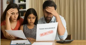 Stressed family reviewing rejected term insurance claim documents with calculator and policy papers