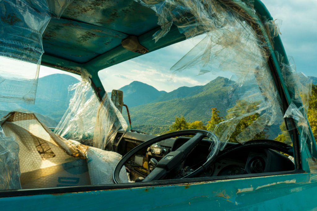 View from inside a damaged truck cab with shattered windshield overlooking a mountainous landscape. #Truck Accident Lawsuit