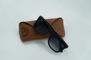 A pair of black Ray-Ban sunglasses resting on a brown leather case.