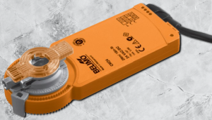 Orange industrial damper actuator on a grey textured surface, symbolizing HVAC system regulation.