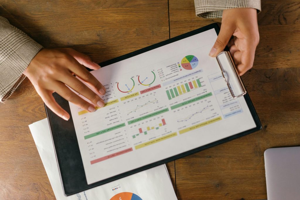 Hands holding a clipboard with colorful financial charts and graphs including pie charts, bar graphs, and line graphs. #Big Data Analytics