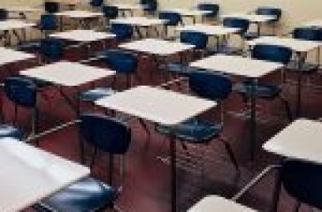 A traditional classroom with rows of blue chairs attached to white desks facing forward. #Modular vs Traditional Classrooms