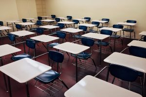 A traditional classroom with rows of blue chairs attached to white desks facing forward. #Modular vs Traditional Classrooms