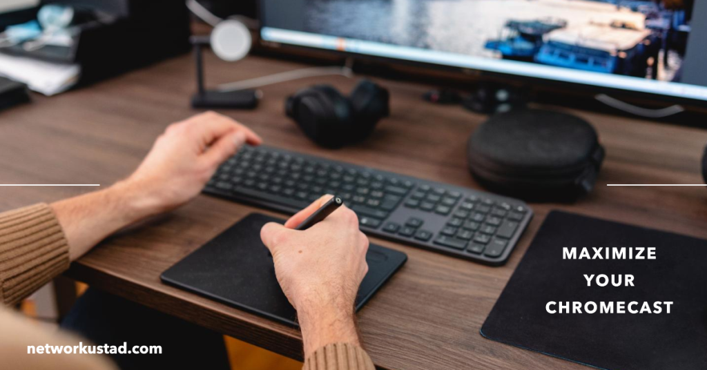 A person’s hands using a stylus on a graphic tablet with a keyboard and headphones on the desk, and a monitor displaying “MAXIMIZE YOUR CHROMECAST” with the website “networkustad.com” visible.