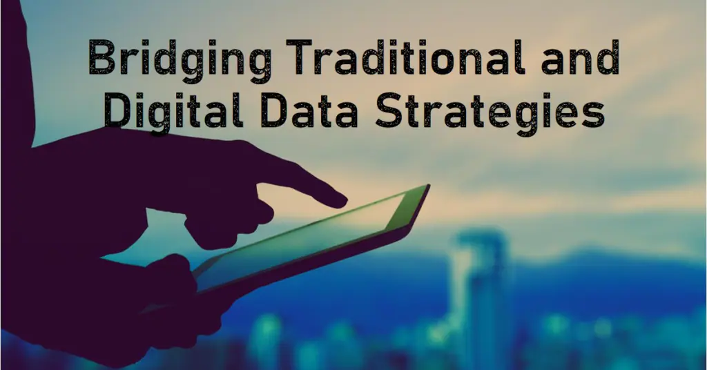 A silhouette of a hand holding and interacting with a tablet, with the text "Bridging Traditional and Digital Data Strategies" overlaid on the image. The background shows a blurred cityscape. debt