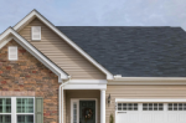 A modern ranch-style house with a beige exterior, stone accents, and a double-car garage.