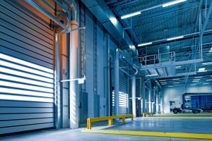 Industrial loading dock with modern garage doors, featuring a truck parked for loading, surrounded by bright, clean, and well-lit interiors.