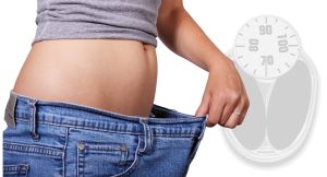 A fit and healthy person measuring their waistline with a tape measure, symbolizing weight loss, fitness, and a healthy lifestyle.