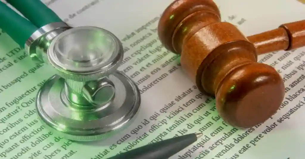 A stethoscope and a wooden gavel placed on top of legal or medical documents.