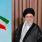Ayatollah Ali Khamenei Sitting In A Room With A Portrait And The Iranian Flag In The Background.