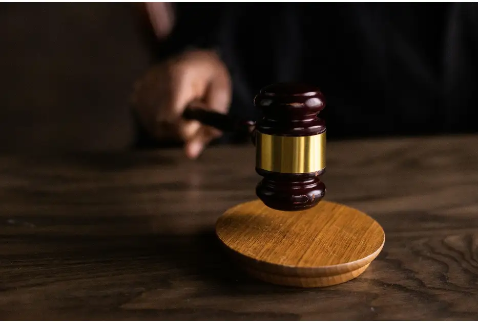 A wooden gavel resting on its sounding block, held by a hand in a judicial robe, symbolizing legal authority.