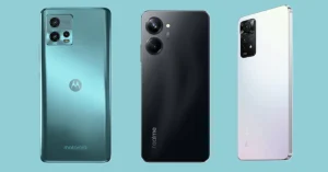 Three budget smartphones side by side: Motorola in teal, realme in black, and Redmi in white, showcasing rear designs and camera modules on a blue background.