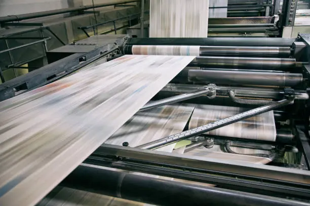 Flexo Printing Equipment in action, showing high-speed paper feed through rollers with multicolor ink for industrial packaging production.