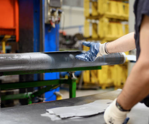 Worker Inspecting Metal Tube During Sheet Metal Fabrication Process In Industrial Manufacturing Facility