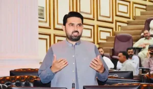 Sohail Afridi speaking passionately in Khyber Pakhtunkhwa assembly hall, gesturing with open arms amid ornate wooden decor and seated parliamentarians.