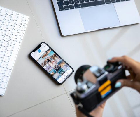 Professional Workspace Showing Smartphone With Digital Portfolio Gallery, Camera, Laptop And Keyboard For Creative Work Presentation