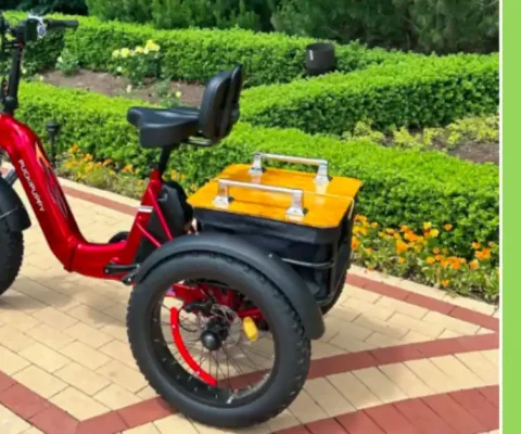 Red Puckipuppy Husky Electric Trike With Fat Tires And Rear Cargo Basket, Parked On A Garden Path Surrounded By Lush Green Hedges And Vibrant Flowers, Showcasing Its Stylish Design For Outdoor Adventures.