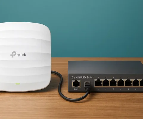 Tp-Link Wireless Access Point Connected To Gigabit Poe Network Switch On Wooden Table With Teal Background
