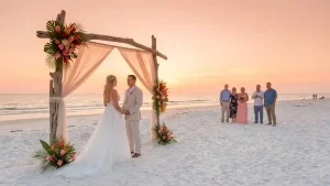 Home 2 Couple exchanging vows on white sandy Sarasota beach with sunset backdrop