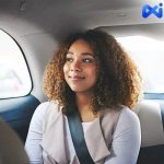 A Happy Female Passenger Riding Safely In The Back Seat Of A Ride-Hailing Cab With A Seatbelt On