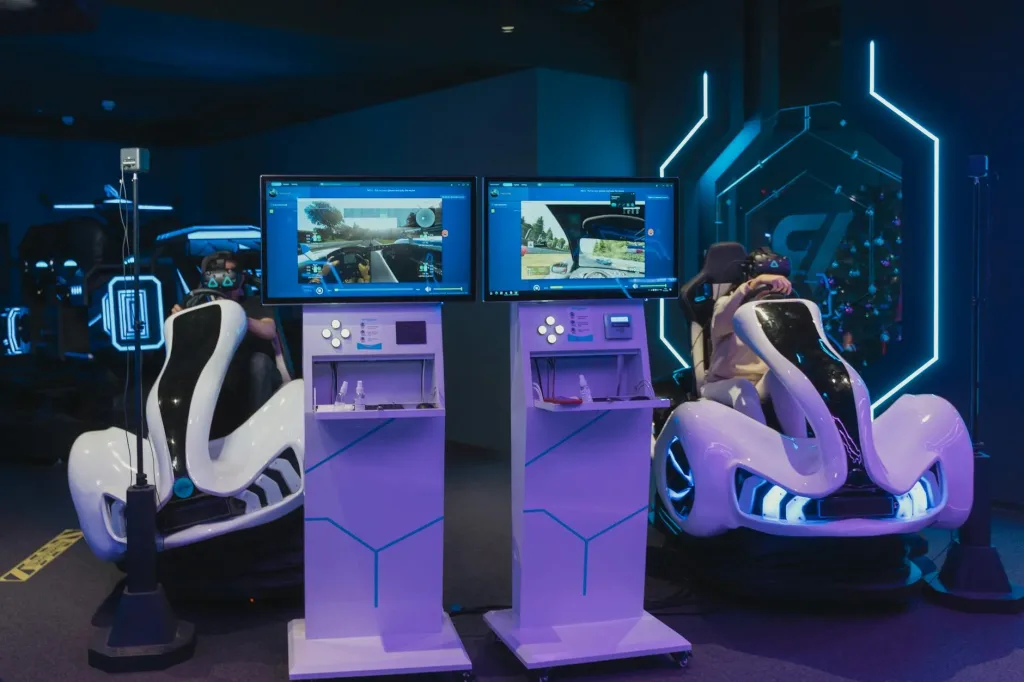 A Network Engineer'S Three-City Trade-Show Circuit: Ces, Mwc, And A Cisco Live Pit Stop 2 Futuristic Gaming Chairs With Vr Headsets And Monitors, Capturing Immersive Gameplay In A Modern Arcade.