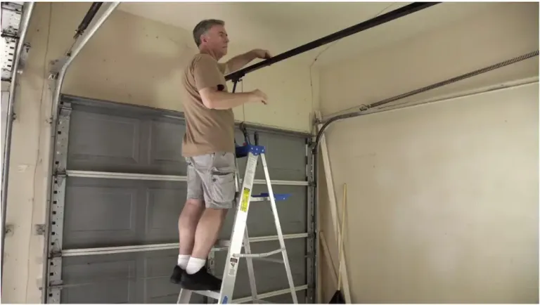 The Perks Of Upgrading Your Garage Door Technology 1 Technician Standing On A Ladder Inspecting The Overhead Garage Door Track And Hardware Inside A Garage